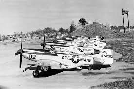 Black-and-white photo of a vintage military aircraft with tail number 02 parked on a dusty airfield.